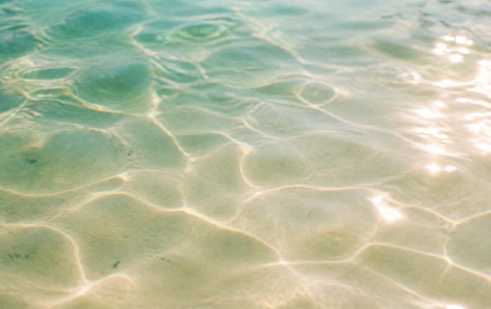 Sunlight refracting through shallow sea water over pale sand